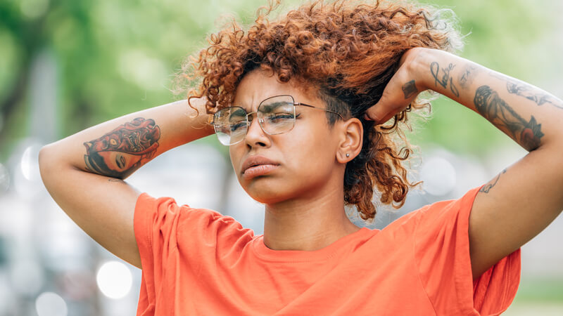 sweating woman holding up her hair in frustration 